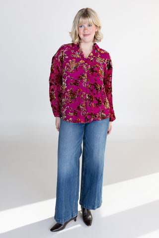 Woman wearing a patterned blouse and blue jeans on a white background