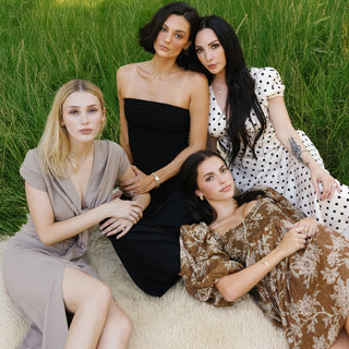Four women sitting on a blanket in a grassy field