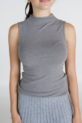 Person wearing a gray sleeveless top against a plain background